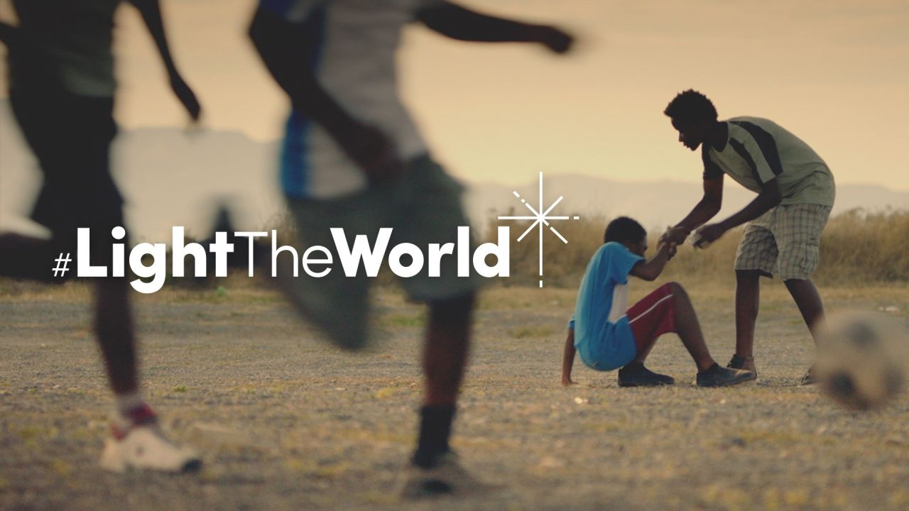 Egy fiú segít egy másiknak felkelni, miután focizás közben elesett, részlet a Légy a világ világossága című rövidfilmből