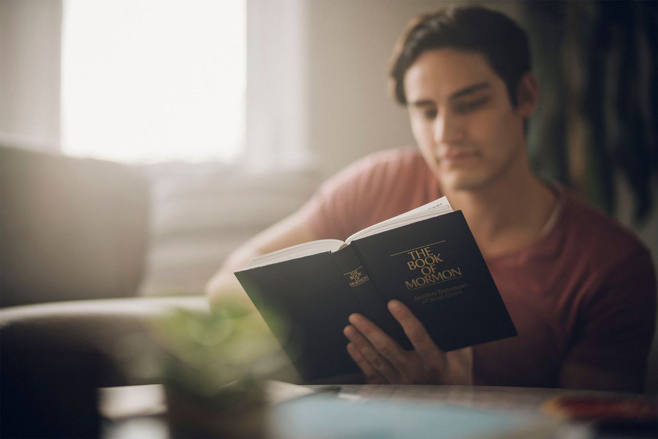 egy férfi a Mormon könyvét tanulmányozza a konyhaasztalánál