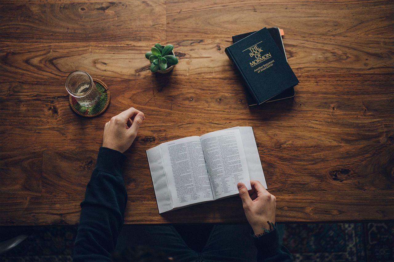 egy férfi a Bibliát és a Mormon könyvét tanulmányozza a konyhaasztalánál
