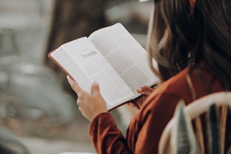 egy nő a Példabeszédek könyvét olvassa a Bibliában